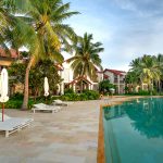 Relaxing poolside view with coconut trees and villas at a tropical resort.