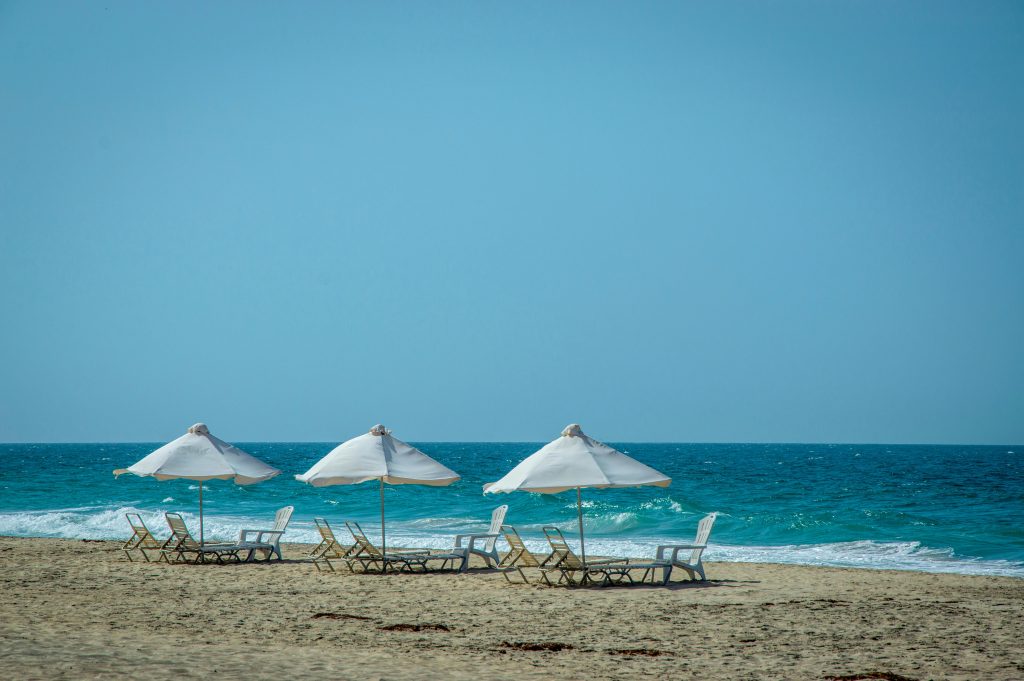 Tranquil beach scene with sunloungers and parasols by blue ocean waves.