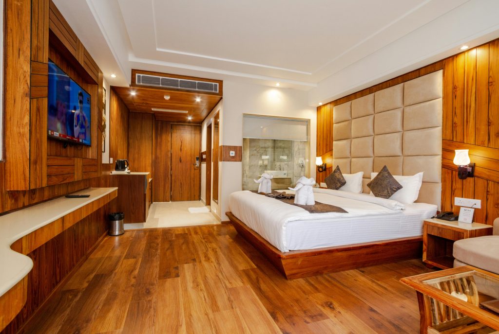 Elegant hotel room featuring wooden decor, a plush bed, and contemporary interior design.