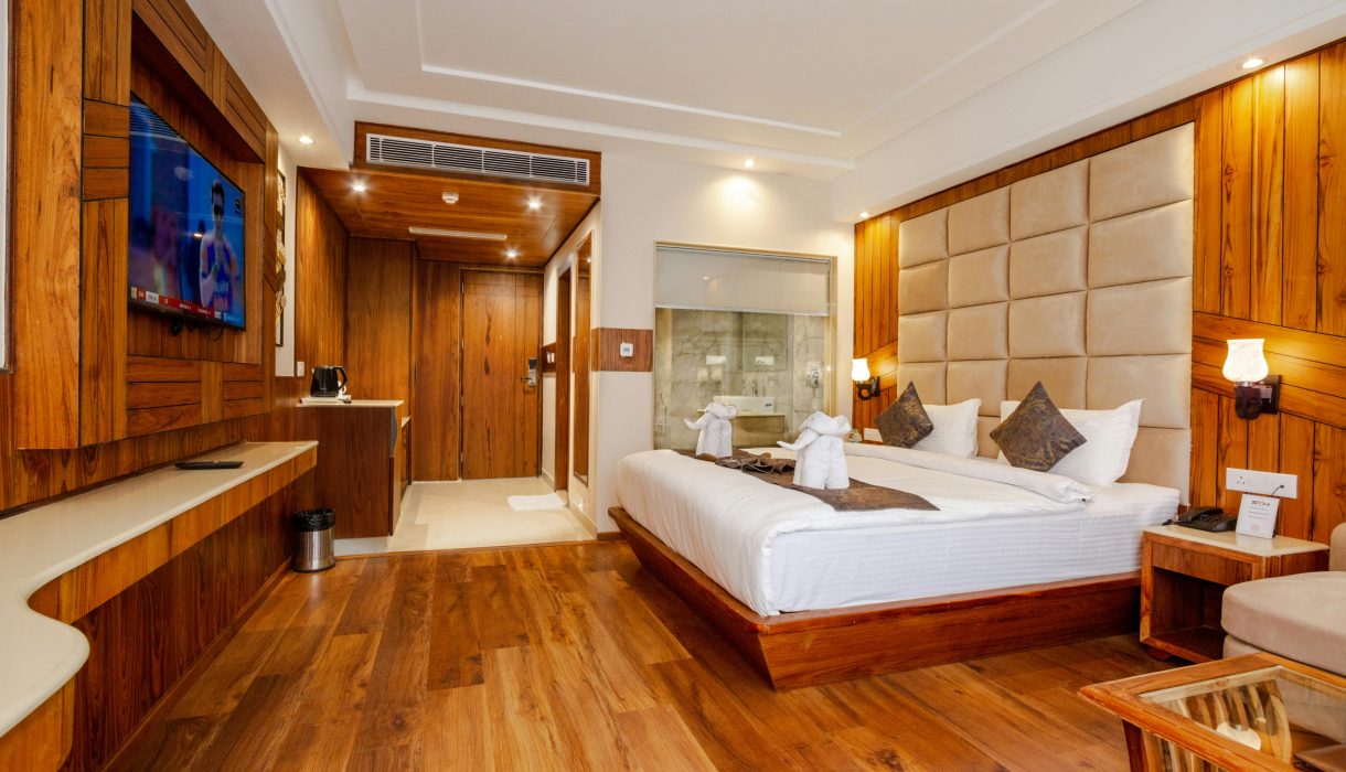 Elegant hotel room featuring wooden decor, a plush bed, and contemporary interior design.