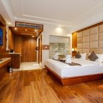 Elegant hotel room featuring wooden decor, a plush bed, and contemporary interior design.