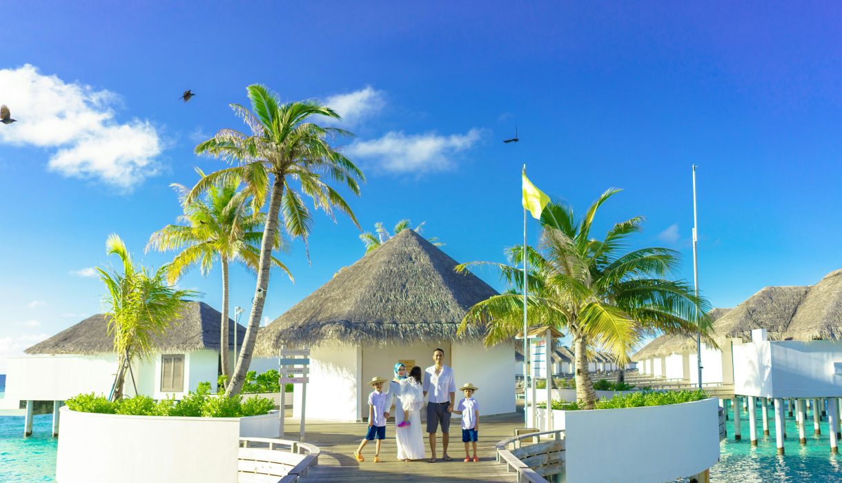A family enjoys a sunny day at a luxurious overwater resort in a tropical paradise.